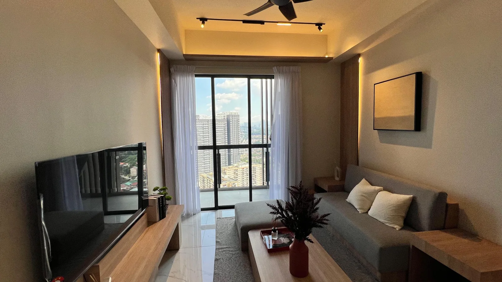 Residensi 38 Bangsar show unit — living area with sofa, feature TV wall and balcony window