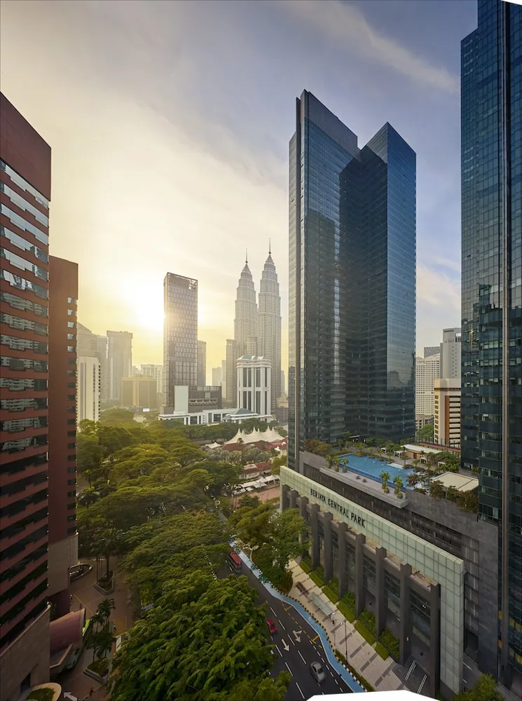 The Ritz-Carlton Residences, Kuala Lumpur — the tower above Berjaya Central Park with the Petronas Twin Towers beyond at sunrise