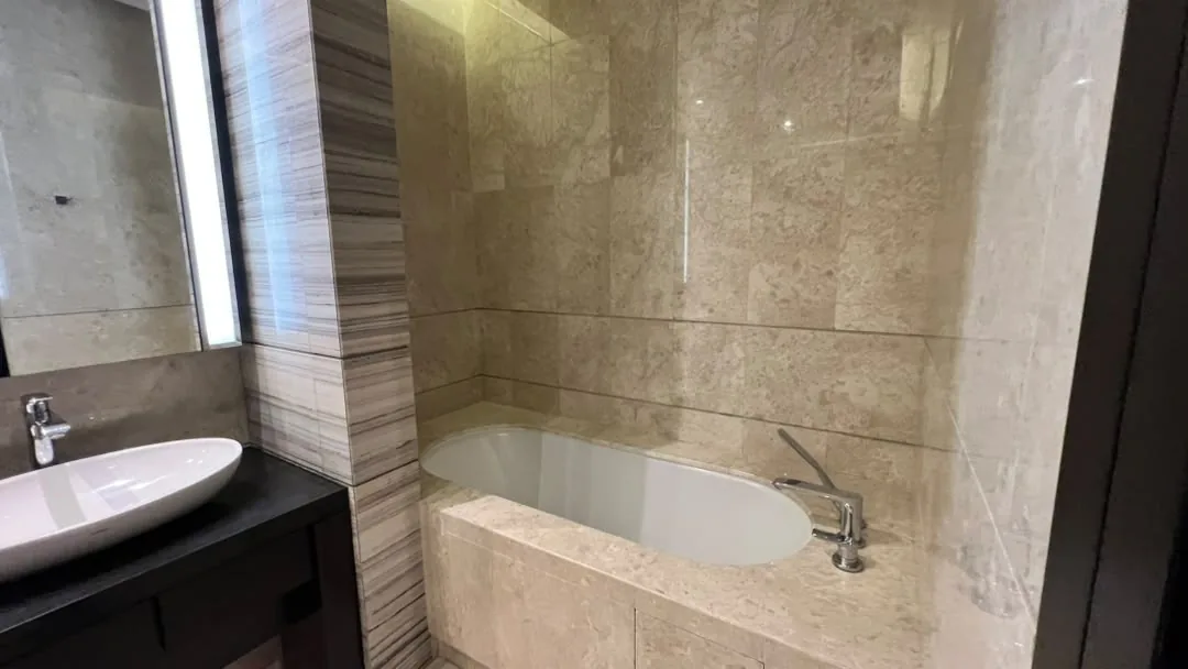 The Ritz-Carlton Residences Kuala Lumpur — bathroom with inset marble bathtub, vessel basin and backlit mirror