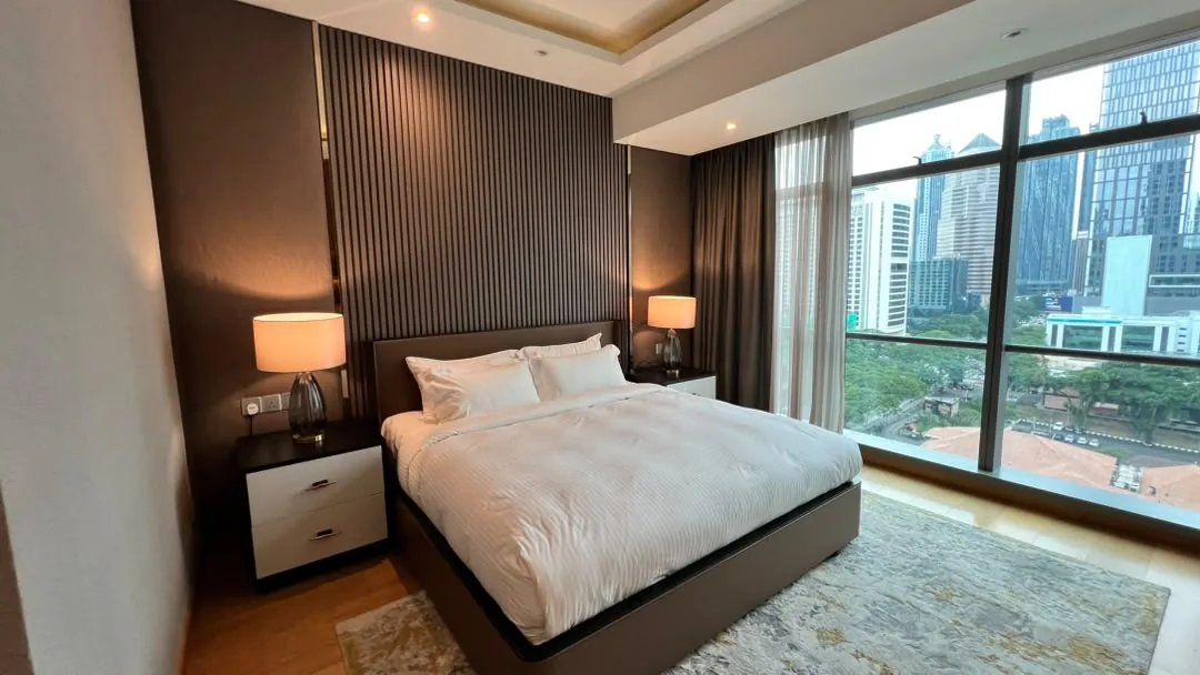 The Ritz-Carlton Residences Kuala Lumpur — master bedroom with fluted timber headboard wall and floor-to-ceiling windows over Kuala Lumpur