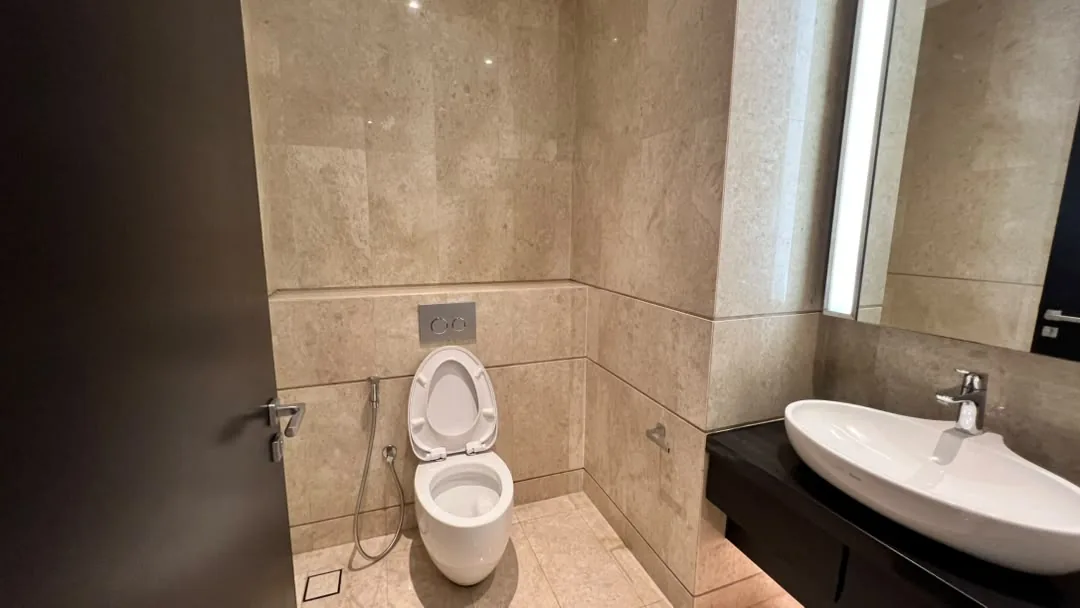 The Ritz-Carlton Residences Kuala Lumpur — powder room finished in marble with vessel basin and backlit mirror