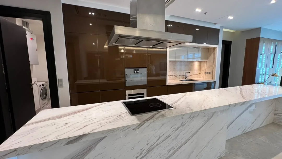 The Ritz-Carlton Residences Kuala Lumpur — kitchen with marble island, induction hob, island extractor, built-in ovens and the utility room beyond